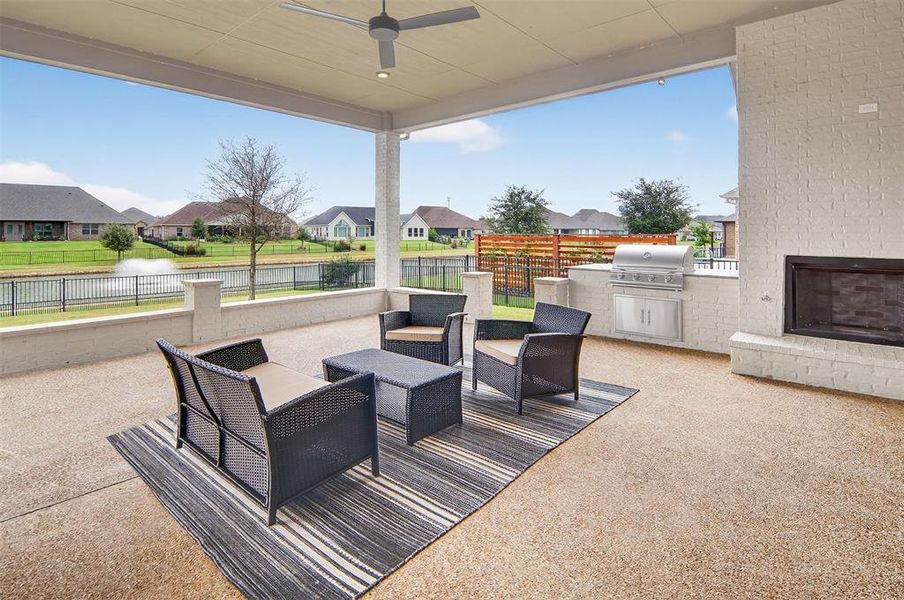 Fenced backyard with a patio area, a residential view, exterior kitchen, a water view, and ceiling fan