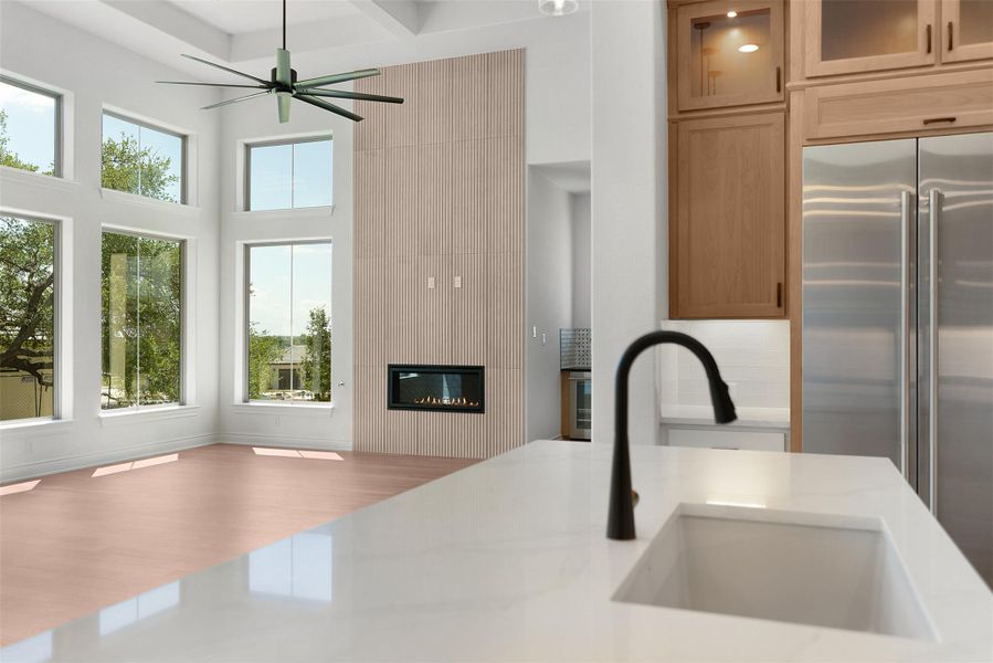 This open-concept living area features a modern fireplace, high ceilings with exposed beams, and a ceiling fan