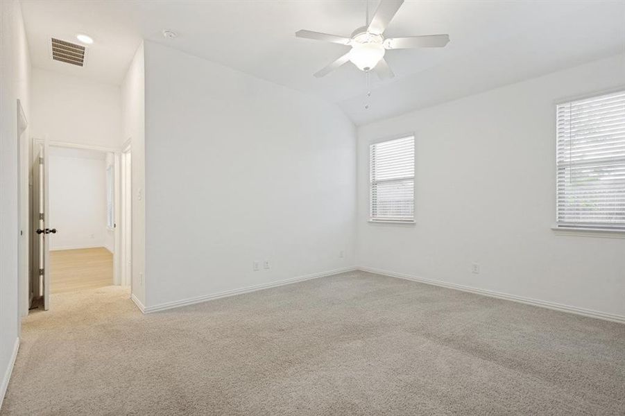 Carpeted room featuring a vaulted ceiling and a ceiling fan with integrated lighting