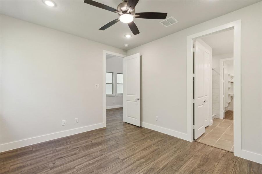 Unfurnished primary bedroom with baseboards, wood finished floors, and recessed lighting