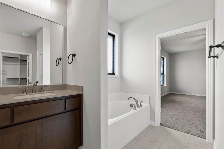 Bathroom with vanity, tile patterned flooring, and a bath