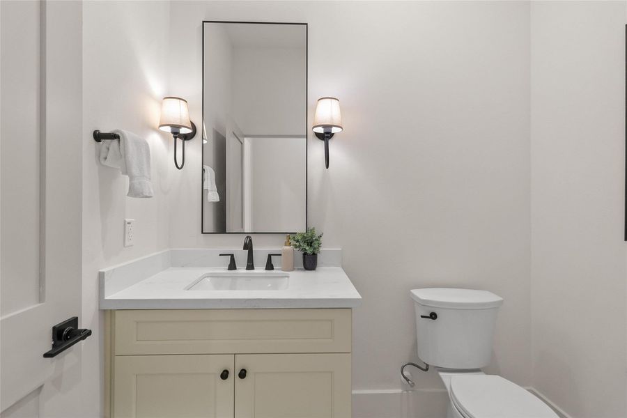 Guests enjoy a beautifully finished powder bath downstairs featuring a sleek vanity, modern fixtures, and timeless finishes.