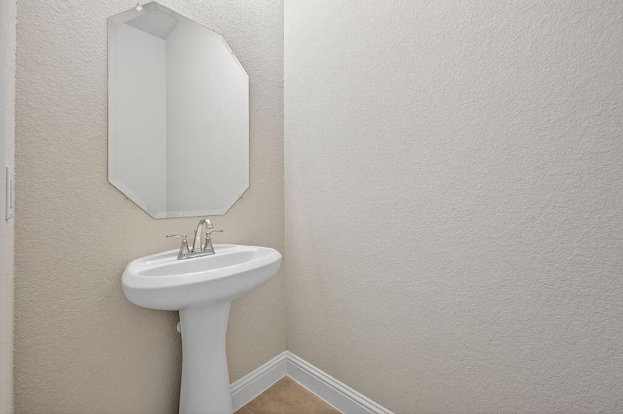 Half bathroom with a textured wall and tile patterned floors