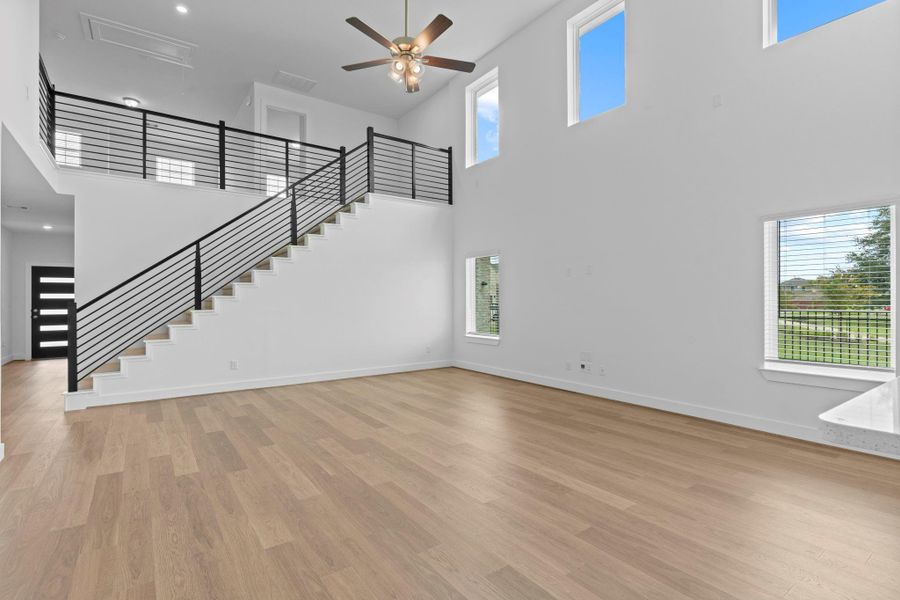 Another angle of the bright family room shows off the soaring ceilings, modern staircase, and massive windows with backyard views—creating an inviting and spacious atmosphere. **Image Representative of Plan Only and May Vary as Built**. Another angle of the bright family room shows off the soaring ceilings, modern staircase, and massive windows with backyard views—creating an inviting and spacious atmosphere. **Image Representative of Plan Only and May Vary as Built**.