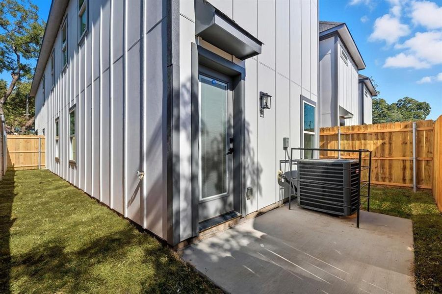 Private backyard space featuring a concrete patio, a full-lite exterior door, and a wooden privacy fence Private backyard space featuring a concrete patio, a full-lite exterior door, and a wooden privacy fence