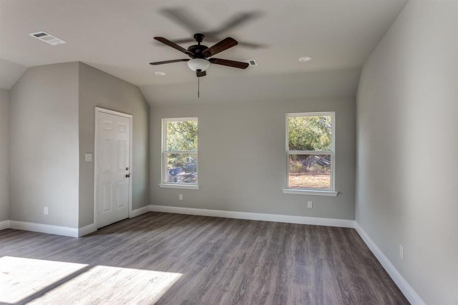 Empty room with dark wood-style flooring, lofted ceiling, and a ceiling fan