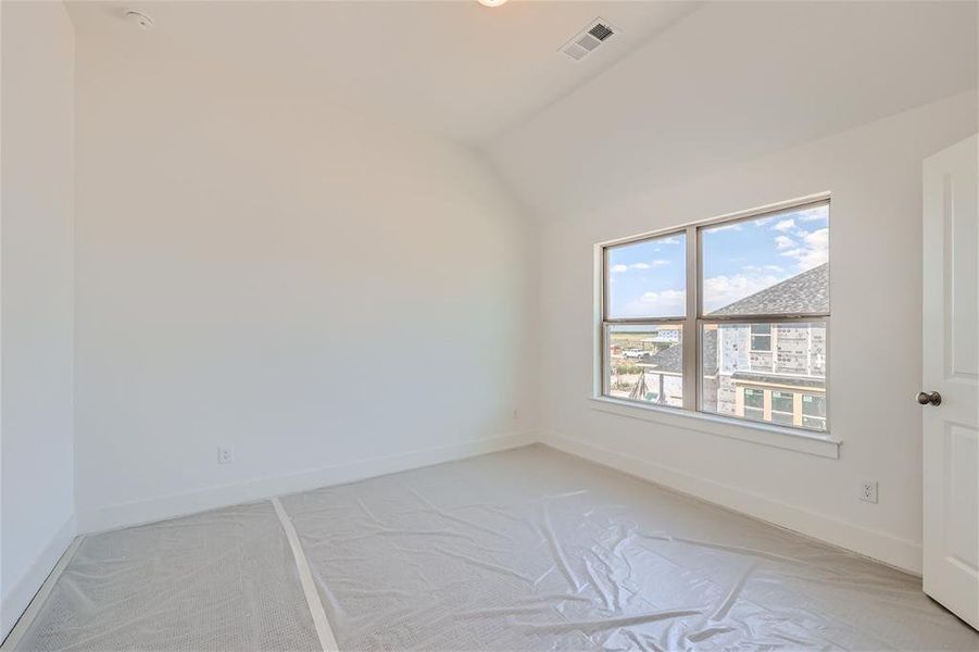 Carpeted spare room with vaulted ceiling