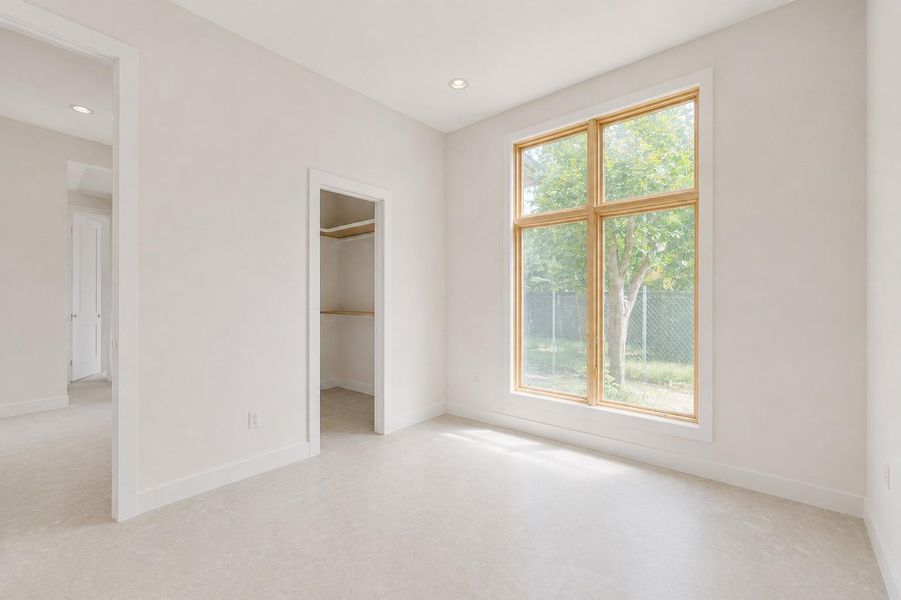 Bright room featuring a large wood-framed window, recessed lighting, and light-colored carpeting