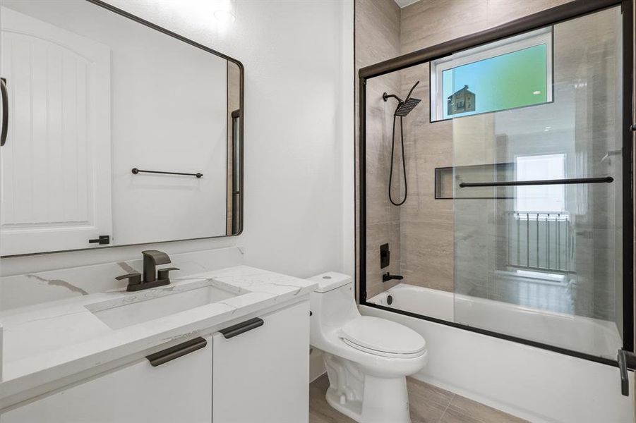 Full bathroom featuring tile patterned floors, vanity, shower / bath combination with glass door, and toilet