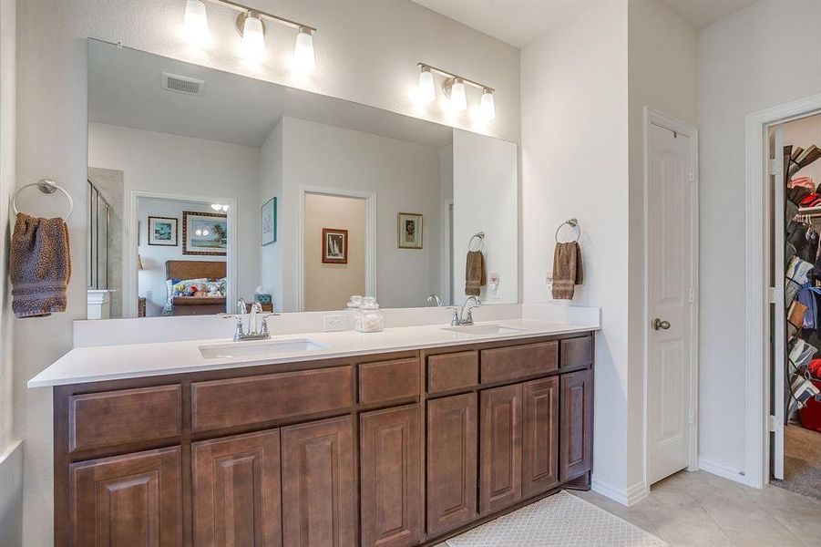 Ensuite bathroom with double vanity, light tile patterned floors, and a spacious closet Ensuite bathroom with double vanity, light tile patterned floors, and a spacious closet