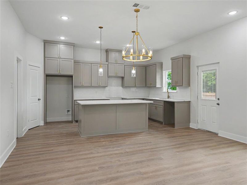 Open-concept kitchen featuring wood-finish flooring, recessed lighting, a central island, gray cabinetry, and a white subway tile backsplash