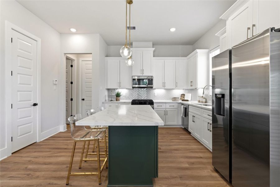 The kitchen is centered around a statement island with contrasting cabinetry, creating both a functional workspace and a natural gathering point within the home. The kitchen is centered around a statement island with contrasting cabinetry, creating both a functional workspace and a natural gathering point within the home.