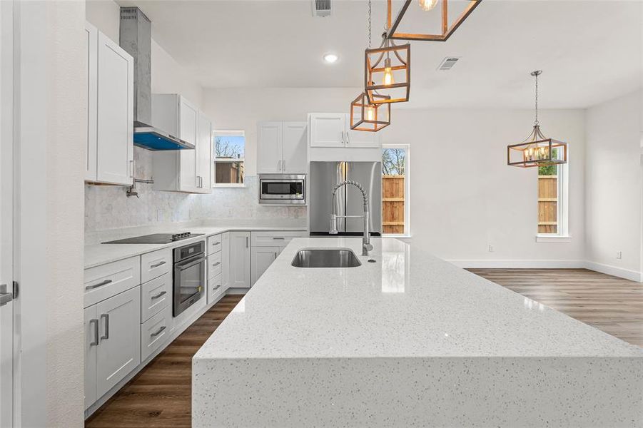 Kitchen featuring light stone counters, wall chimney exhaust hood, decorative light fixtures, dark wood-type flooring, and recessed lighting Kitchen featuring light stone counters, wall chimney exhaust hood, decorative light fixtures, dark wood-type flooring, and recessed lighting