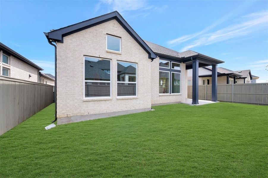 Rear view of property with a fenced backyard, a patio, and brick siding