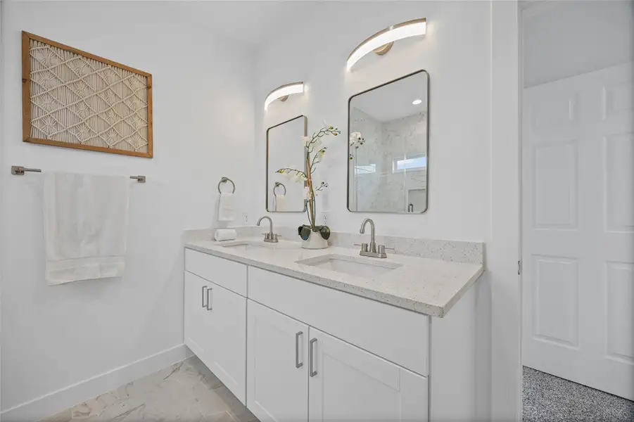 A well-lit primary bathroom vanity provides dual sinks with ample counter space. A well-lit primary bathroom vanity provides dual sinks with ample counter space.