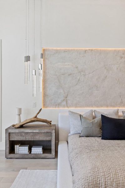 Custom wall paneling with ambient backlighting sets a serene tone for this elegant sleeping space.