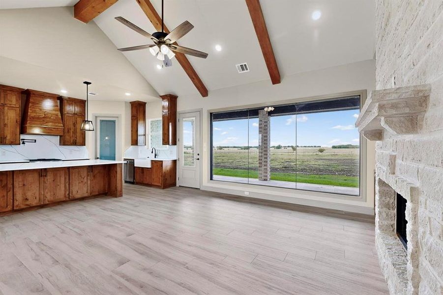 Kitchen featuring brown cabinetry, beam ceiling, light countertops, light wood finished floors, and custom exhaust hood Kitchen featuring brown cabinetry, beam ceiling, light countertops, light wood finished floors, and custom exhaust hood