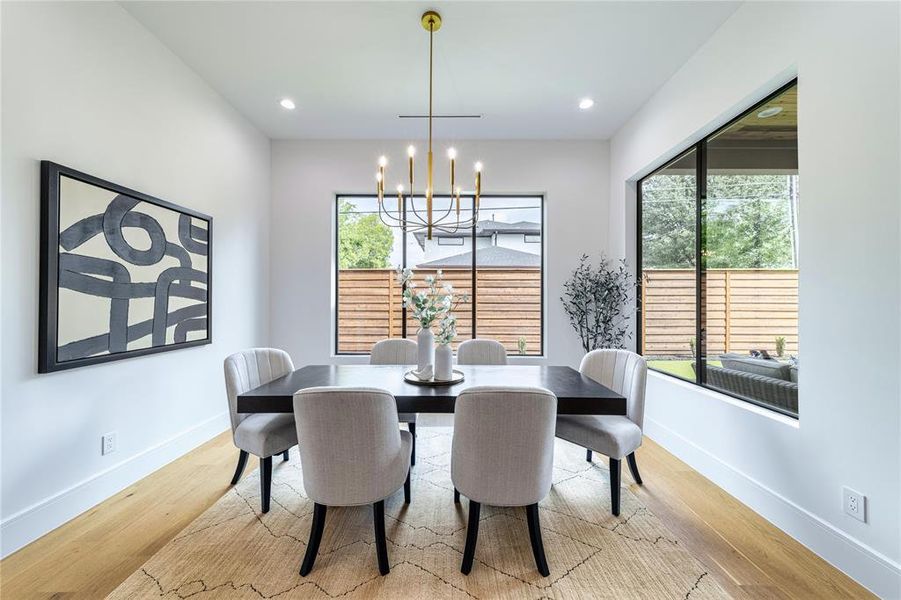 Dining area with light wood-style floors and suspended lighting