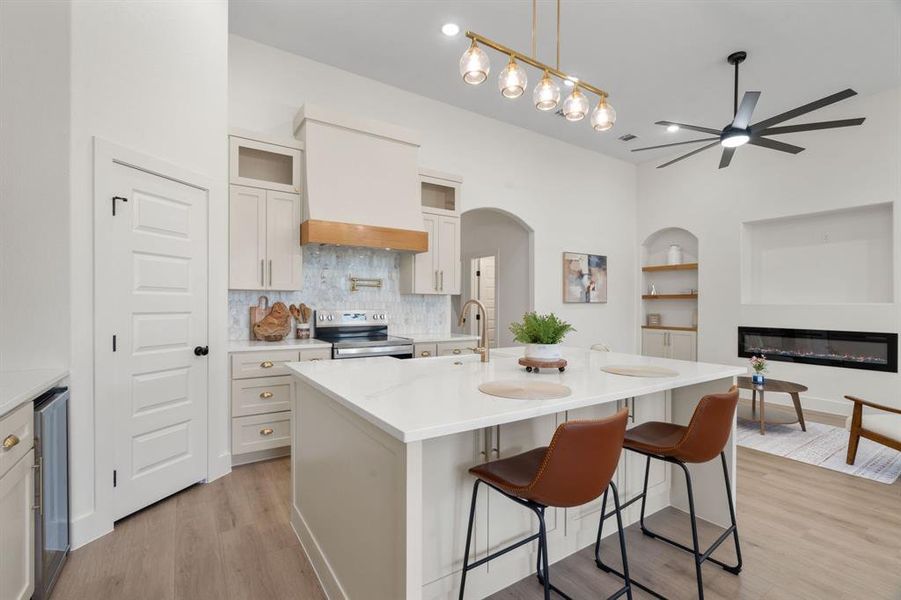 Kitchen with built in features, a kitchen bar, decorative light fixtures, a glass covered fireplace, and a kitchen island with sink Kitchen with built in features, a kitchen bar, decorative light fixtures, a glass covered fireplace, and a kitchen island with sink