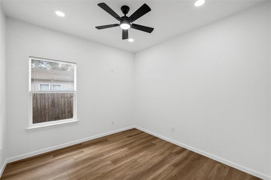 Bright room featuring wood-finish flooring, a contemporary ceiling fan, recessed lighting, and a single window with horizontal blinds Bright room featuring wood-finish flooring, a contemporary ceiling fan, recessed lighting, and a single window with horizontal blinds