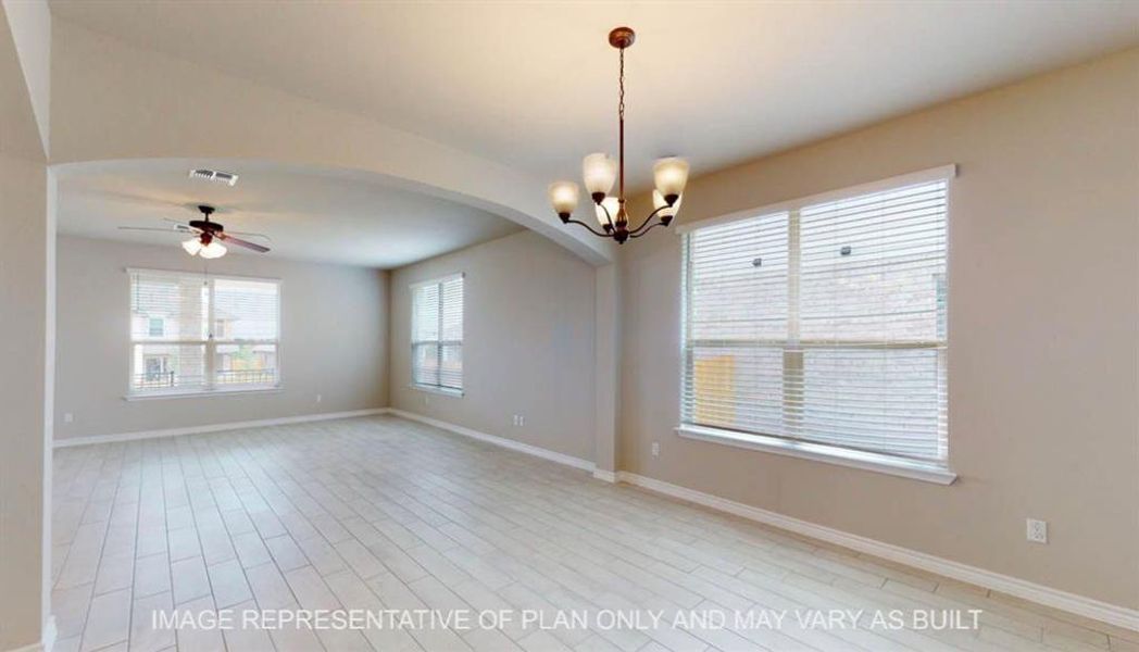 Empty room with a ceiling fan, arched walkways, a chandelier, and light wood-style flooring Empty room with a ceiling fan, arched walkways, a chandelier, and light wood-style flooring