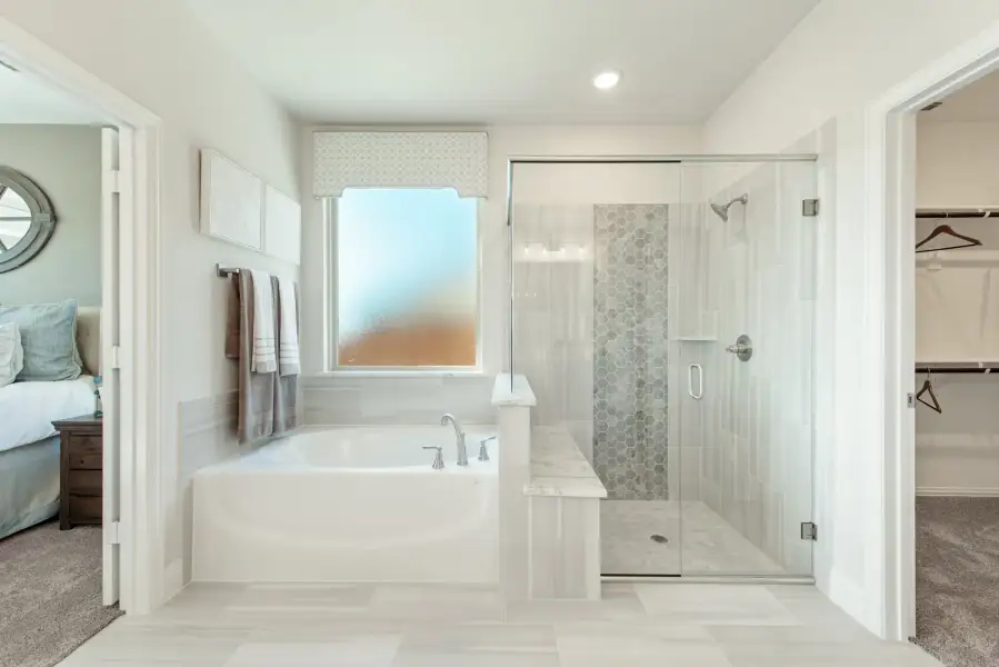 Master bathroom with soaking tub, glass-enclosed shower, and walk-in closet access