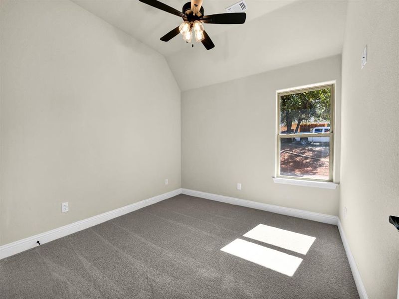 Unfurnished room featuring carpet floors, vaulted ceiling, and ceiling fan