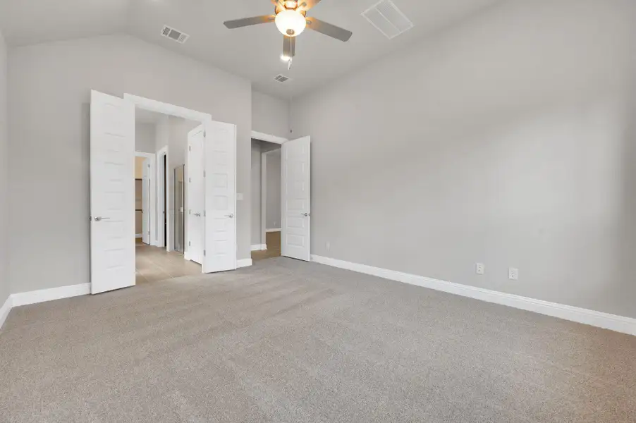Unfurnished bedroom with carpet flooring, vaulted ceiling, and a ceiling fan