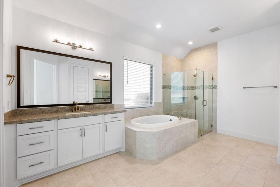 Primary ensuite bathroom with dual vanities, large soaking tub, separate shower, tons of storage space and spacious walk-in closet