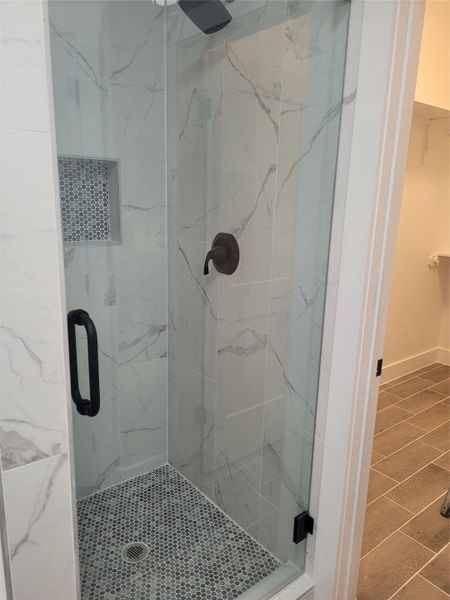 Bathroom featuring a marble finish shower, a walk in closet, and tile patterned flooring
