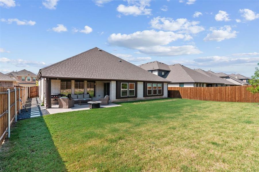 Back of house featuring a fenced backyard, an outdoor hangout area, brick siding, roof with shingles, and a patio area