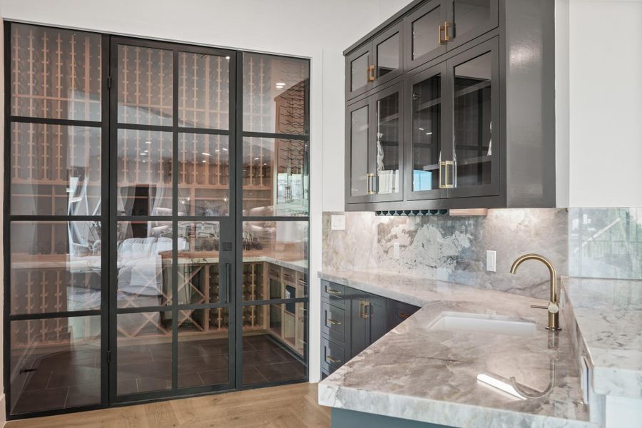 Second wet bar found on the second floor, neighboring the living room. Complete with quartzite countertops, custom, built on site, cabinetry, ice machine, and a temperature controlled wine room.