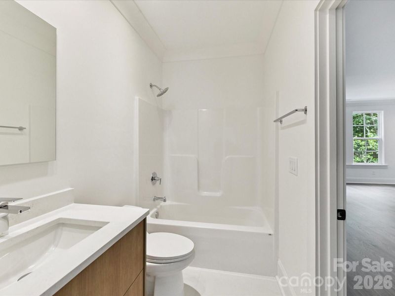 Private ensuite bathroom off the bonus room featuring a vanity and tub/shower combination for added convenience.