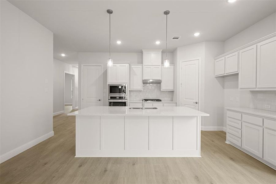 Kitchen with stainless steel appliances, decorative backsplash, white cabinetry, light countertops, and recessed lighting