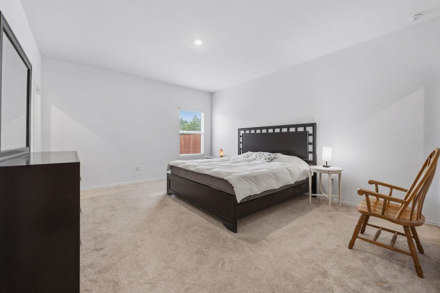 Spacious bedroom featuring neutral carpeting, white walls, and a recessed ceiling light