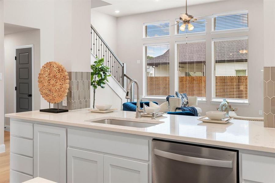 Kitchen with stainless steel dishwasher, white cabinetry, ceiling fan, sink, and light hardwood / wood-style flooring