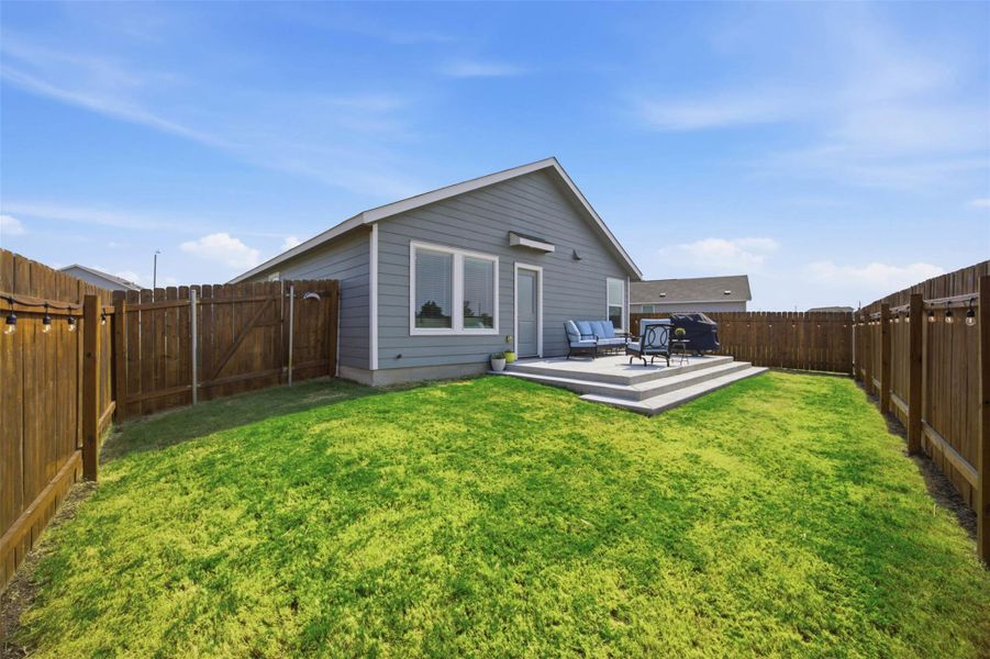 A spacious backyard features a level lawn enclosed by a wooden privacy fence.
