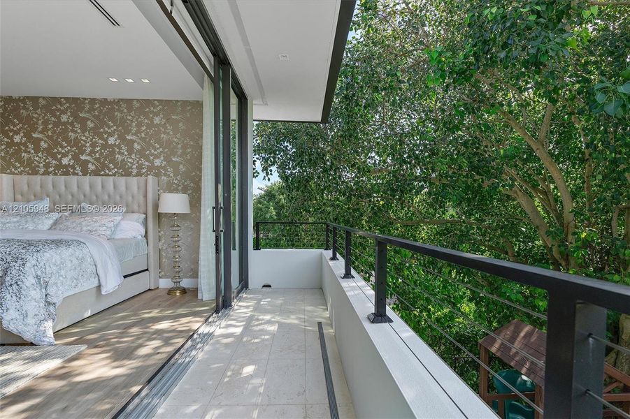 Private balcony with stone flooring, metal railings, recessed lighting, and large-format sliding glass doors
