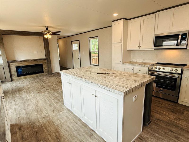 Kitchen with a center island, a ceiling fan, light countertops, appliances with stainless steel finishes, and wood finished floors
