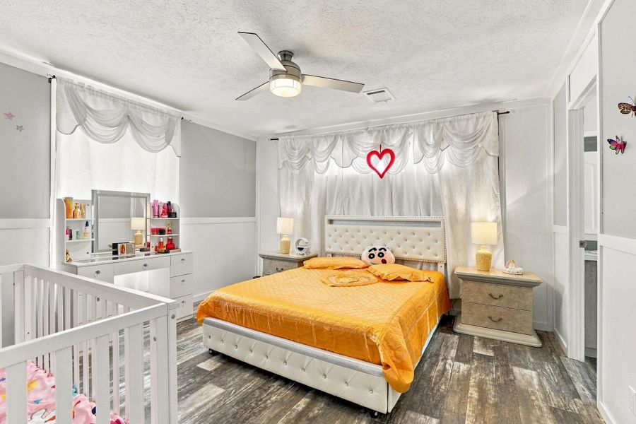 Rustic wood-look flooring and classic wainscoting details anchor this inviting bedroom space.