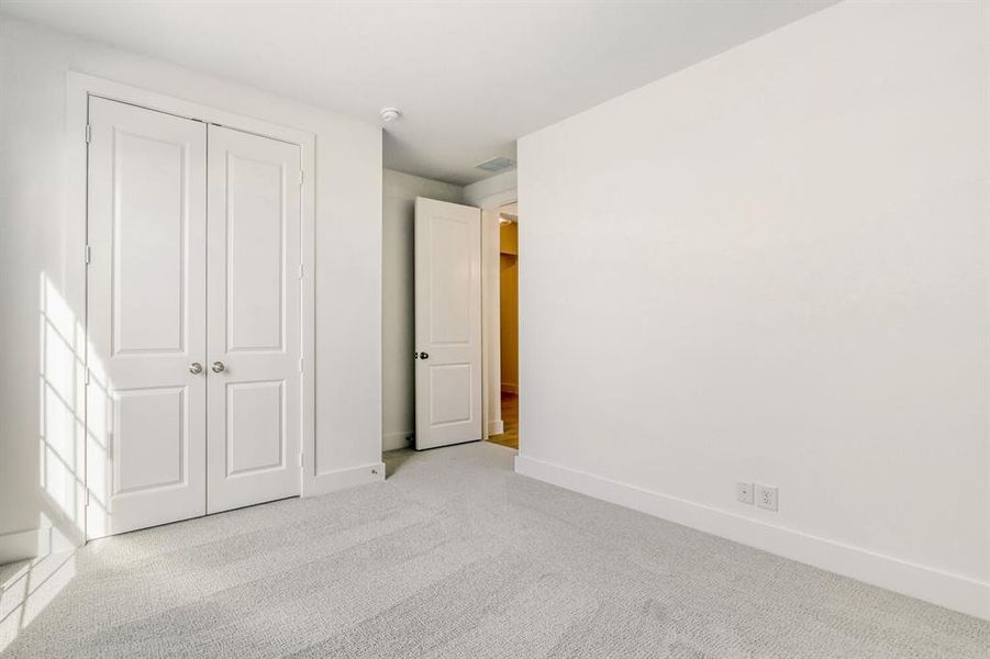Unfurnished bedroom with light carpet and a closet