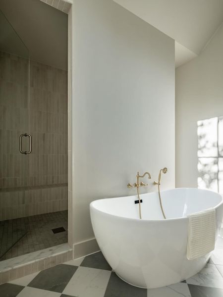 A freestanding soaking tub complements a tiled walk-in shower in this luxurious bathroom.