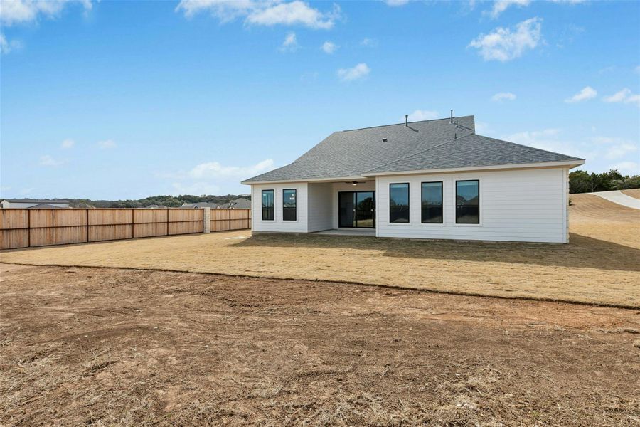 Rear view of house featuring a patio area and roof with shingles