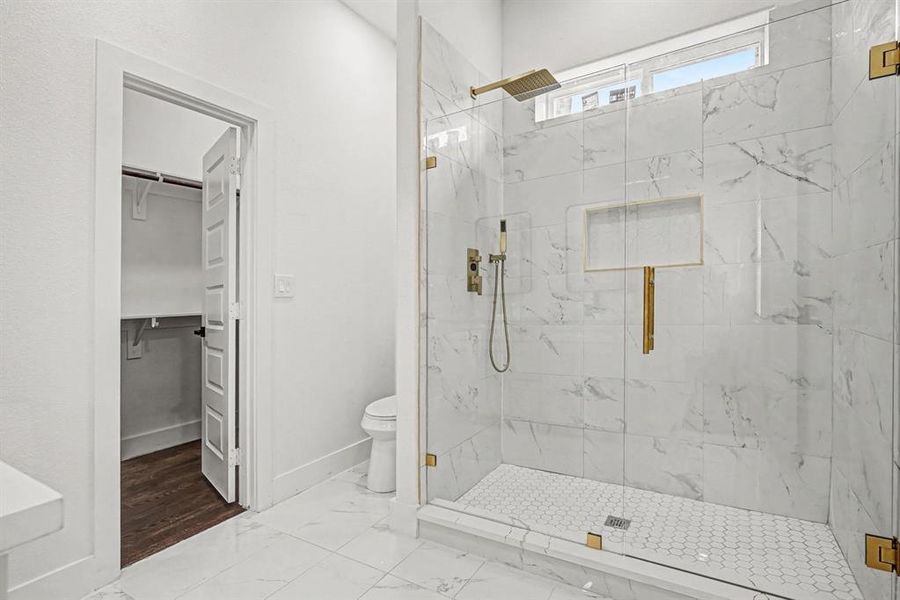 Bathroom with a tiled shower, shelf inset, window for ambient light, rain shower head and additional shower spray.