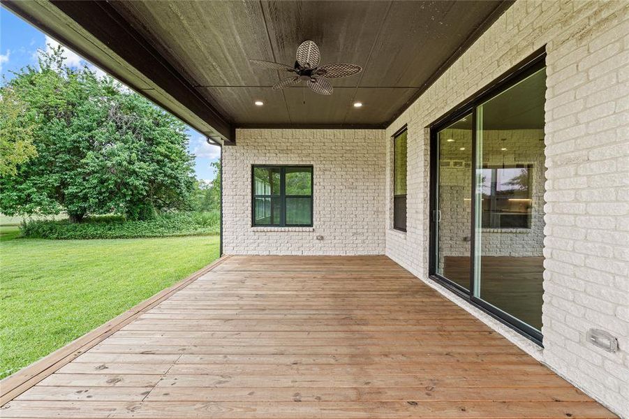 Wooden terrace featuring ceiling fan and a yard