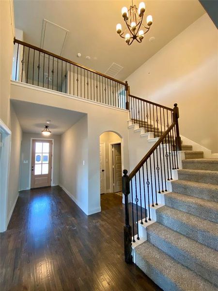 Elegant cathedral ceiling with chandelier and wrought iron spindles on the staircase