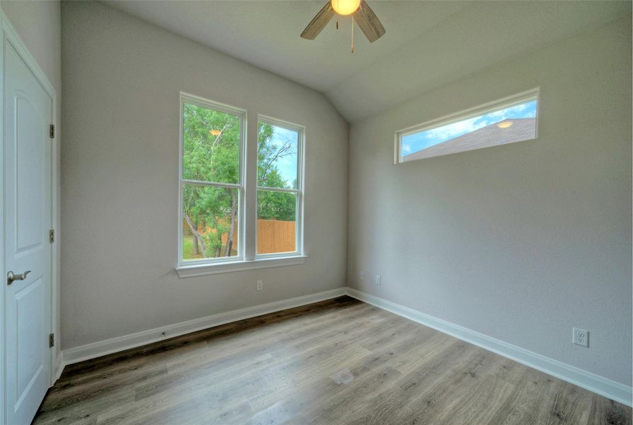 Spare room featuring wood finished floors, ceiling fan, and vaulted ceiling Spare room featuring wood finished floors, ceiling fan, and vaulted ceiling