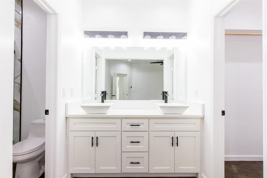 Bathroom featuring tile patterned floors, double vanity, and toilet