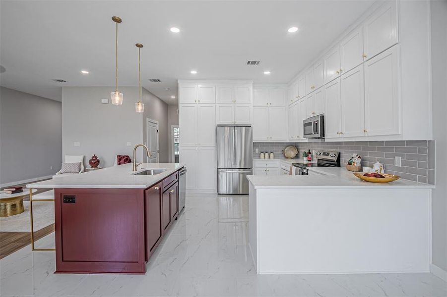 Kitchen with a breakfast bar area, stainless steel appliances, two tone cabinetry, light marble finish floors, and light stone countertops