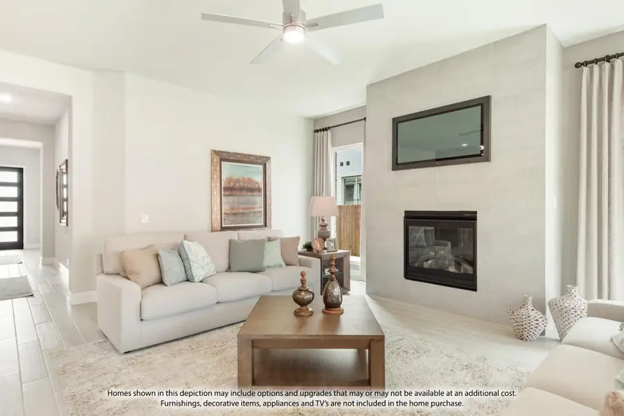 Living room with tile fireplace, wall-mounted TV, ceiling fan, and light gray sofa on wood-look floors Living room with tile fireplace, wall-mounted TV, ceiling fan, and light gray sofa on wood-look floors